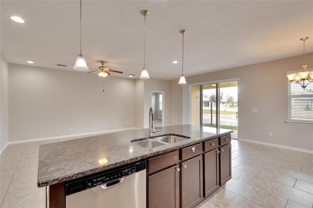 kitchen featuring pendant lighting, dishwasher, a kitchen island with sink, stone counters, and sink