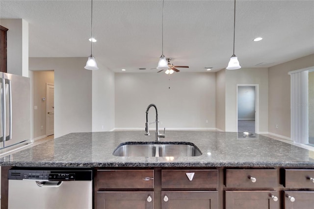 kitchen with pendant lighting, dishwasher, dark stone countertops, and sink