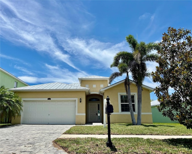 442 Bahama Grande Blvd, Apollo Beach, FL 33572 - view of front facade with a standing seam roof, an attached garage, decorative driveway, stucco siding, and a metal roof