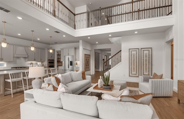 living room with a towering ceiling and light hardwood / wood-style flooring