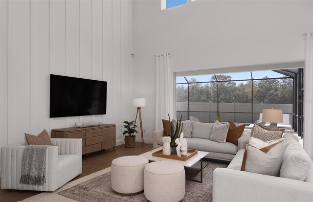 living room with dark hardwood / wood-style flooring, plenty of natural light, and a towering ceiling