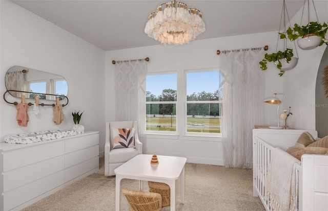 bedroom featuring a crib, light carpet, and an inviting chandelier