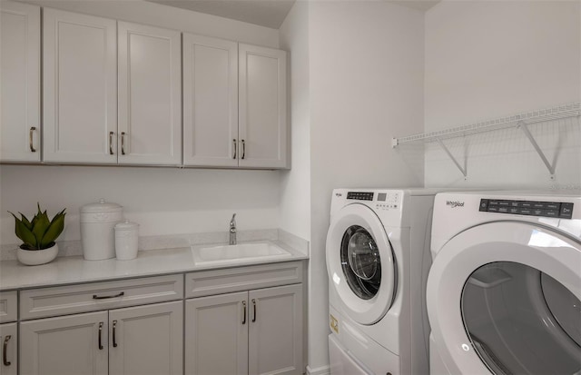 laundry room featuring washing machine and clothes dryer, sink, and cabinets