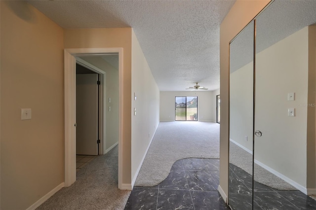 hallway featuring dark carpet and a textured ceiling