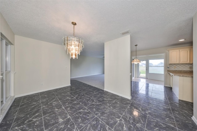 spare room featuring a chandelier and a textured ceiling