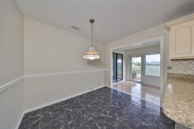 unfurnished dining area featuring a textured ceiling