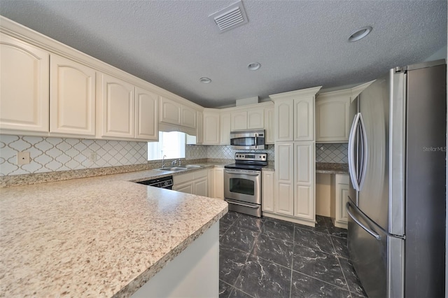 kitchen with backsplash, sink, stainless steel appliances, and cream cabinetry