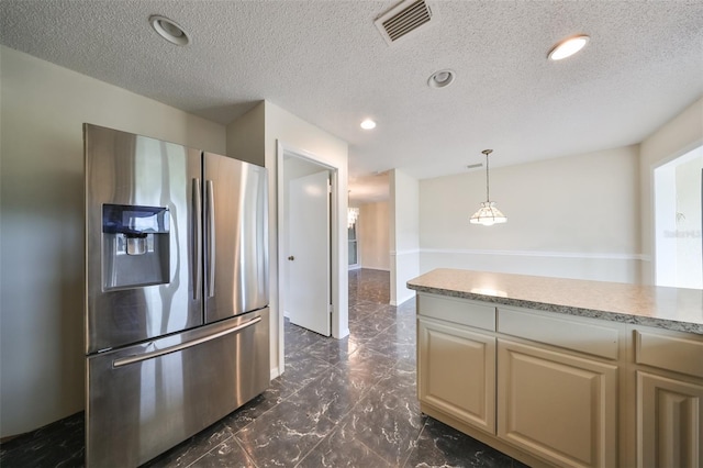 kitchen featuring a textured ceiling, stainless steel refrigerator with ice dispenser, and hanging light fixtures