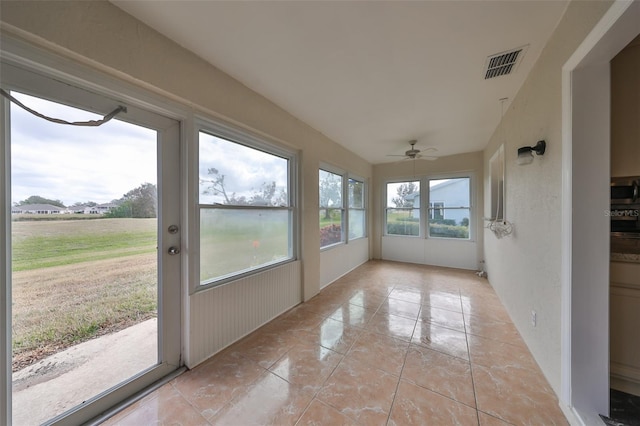 unfurnished sunroom with a wealth of natural light and ceiling fan