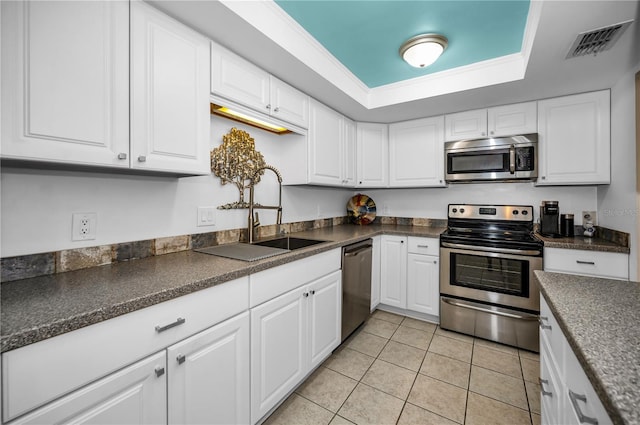 kitchen featuring white cabinetry, sink, light tile patterned floors, a tray ceiling, and stainless steel appliances