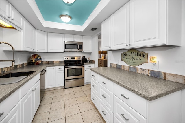 kitchen featuring sink, a tray ceiling, stainless steel appliances, and white cabinets