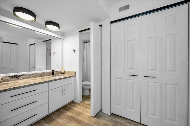 bathroom with vanity, hardwood / wood-style flooring, and toilet