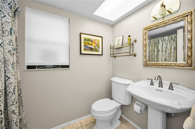 bathroom with sink, toilet, a skylight, and tile patterned flooring