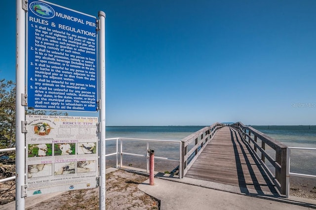 view of dock with a water view and a beach view