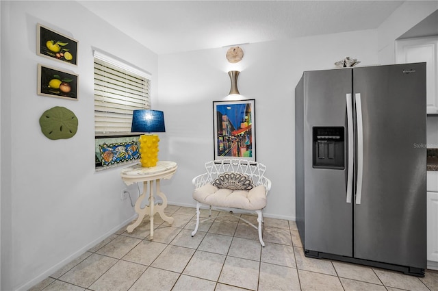 kitchen with stainless steel fridge, white cabinets, and light tile patterned flooring