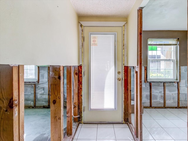 doorway with light tile patterned floors and a textured ceiling