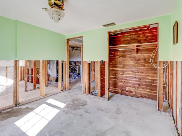 unfurnished bedroom with wooden walls and concrete flooring