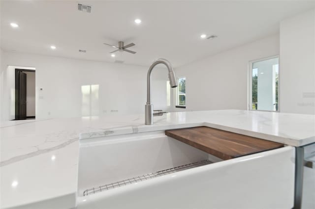 kitchen with ceiling fan, sink, and light stone counters