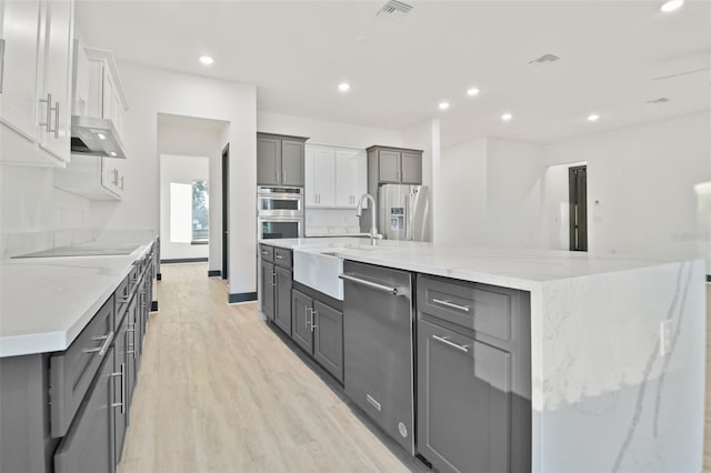 kitchen featuring white cabinets, a spacious island, gray cabinets, light hardwood / wood-style floors, and stainless steel appliances