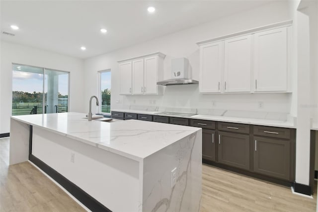 kitchen featuring sink, light wood-type flooring, white cabinetry, and wall chimney range hood