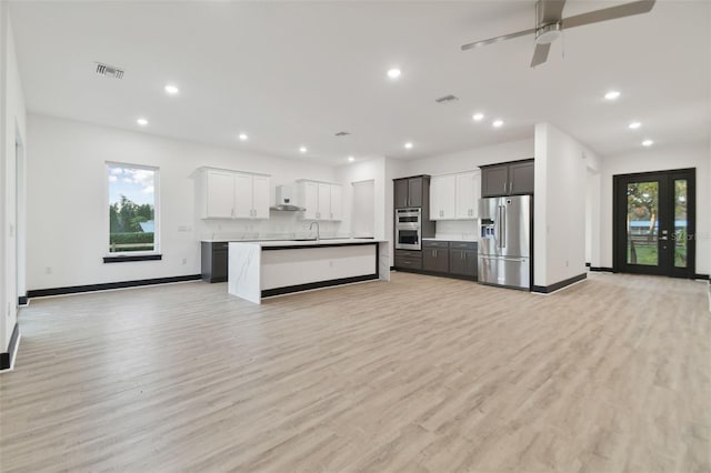 kitchen featuring stainless steel appliances, plenty of natural light, a kitchen island with sink, and light hardwood / wood-style flooring