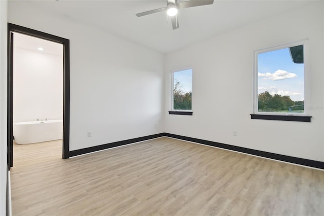 empty room featuring ceiling fan, a healthy amount of sunlight, and light hardwood / wood-style floors