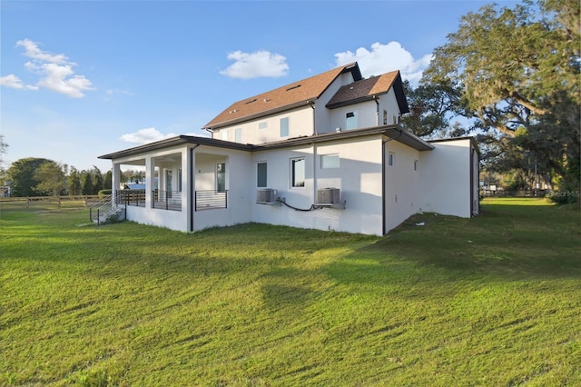 rear view of property with a porch, a yard, and central air condition unit