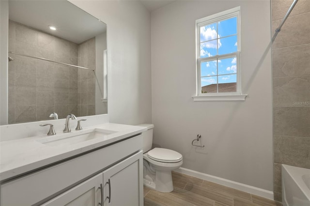 full bathroom featuring tiled shower / bath, vanity, and toilet