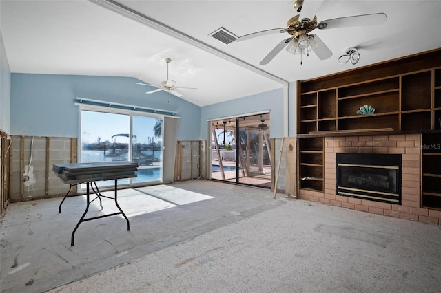 living room featuring plenty of natural light, ceiling fan, a fireplace, and vaulted ceiling