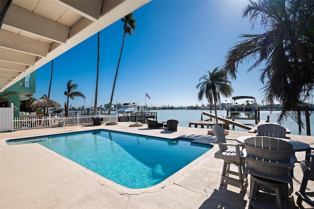 view of pool featuring a dock, a water view, and a patio