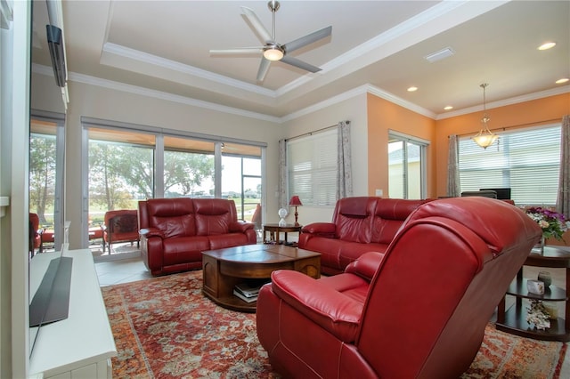 tiled living room with a tray ceiling, ceiling fan, and ornamental molding