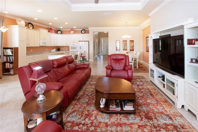 tiled living room with a raised ceiling, an inviting chandelier, ornamental molding, and sink