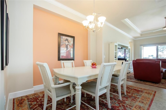 tiled dining area with ceiling fan with notable chandelier, a tray ceiling, and ornamental molding