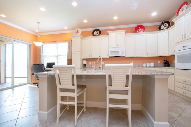 kitchen with white appliances, a kitchen bar, a kitchen island with sink, white cabinets, and ornamental molding