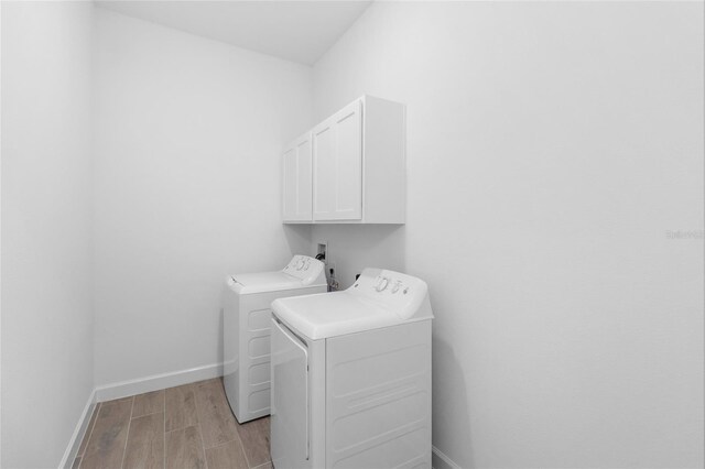 clothes washing area featuring washing machine and dryer and cabinets