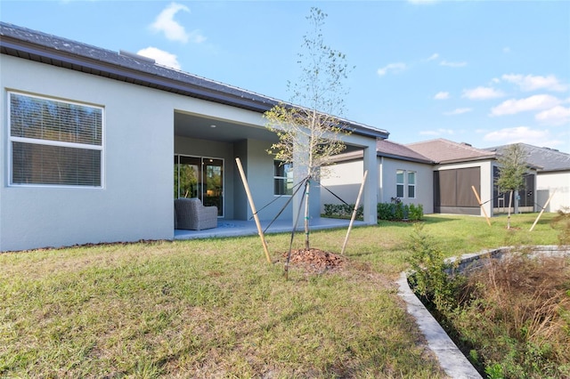 back of house with a lawn and a patio