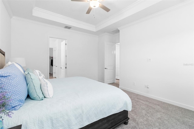 carpeted bedroom with ceiling fan, ornamental molding, and a raised ceiling