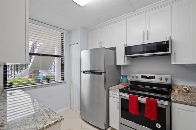 kitchen featuring light tile patterned flooring, light stone countertops, white cabinetry, and appliances with stainless steel finishes