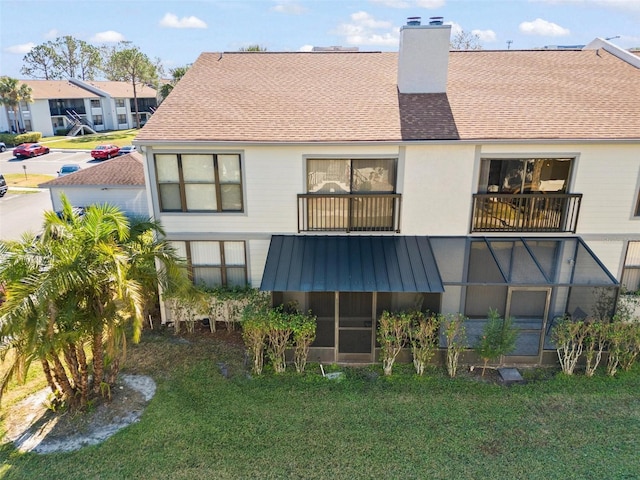 rear view of property featuring a lawn and a balcony