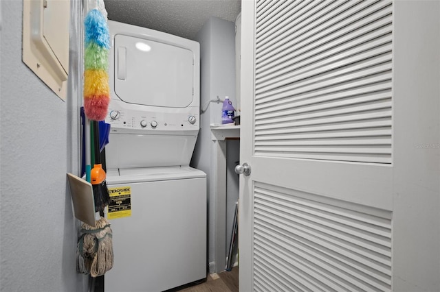 laundry area featuring a textured ceiling and stacked washer and clothes dryer