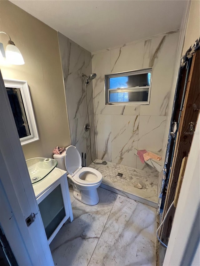 bathroom featuring a tile shower, vanity, and toilet