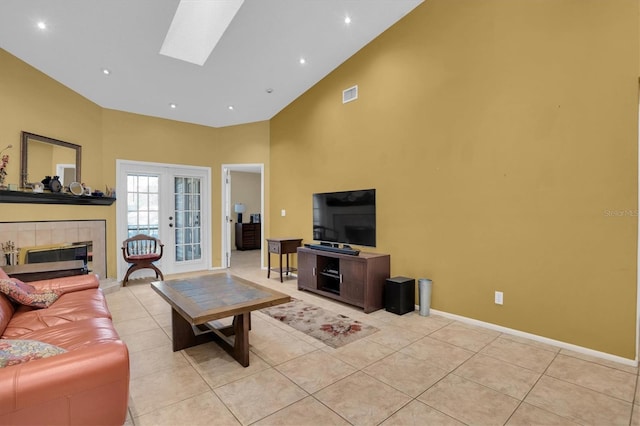 tiled living room with french doors, a fireplace, high vaulted ceiling, and a skylight