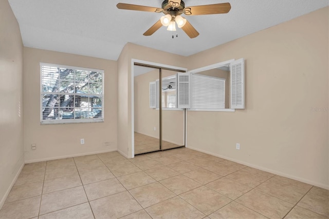 unfurnished bedroom with light tile patterned floors, a textured ceiling, a closet, and ceiling fan