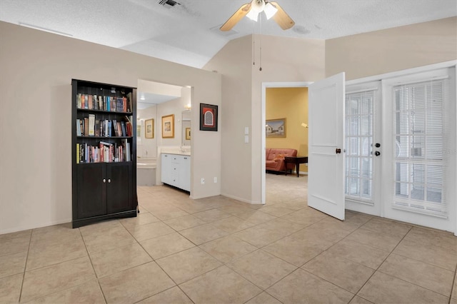 tiled spare room with a textured ceiling, ceiling fan, and lofted ceiling