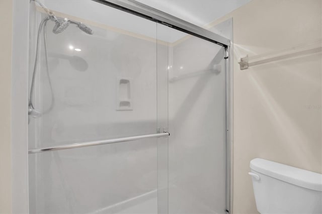 bathroom featuring toilet and a shower with shower door