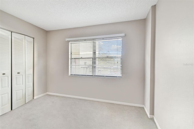 unfurnished bedroom with light carpet, a textured ceiling, and a closet