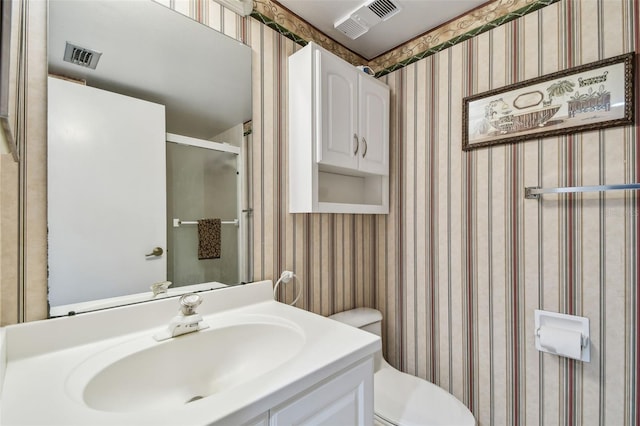 bathroom featuring vanity, a shower with shower door, and toilet