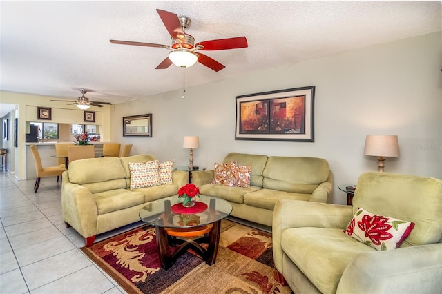 living room featuring ceiling fan, a textured ceiling, and light tile patterned floors