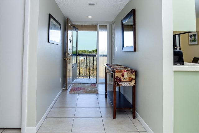 doorway featuring light tile patterned floors, expansive windows, and a textured ceiling