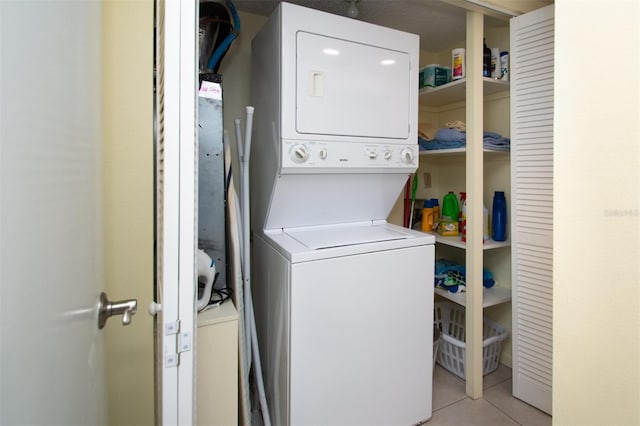 laundry area with light tile patterned flooring and stacked washer / drying machine